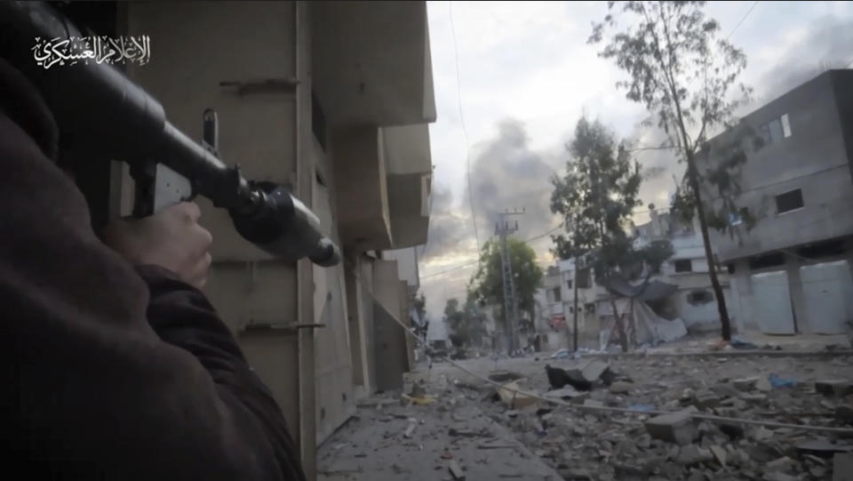 In this image from video released by Hamas on Dec. 2, 2023, a Hamas fighter aims an Al-Yasin 105 rocket at an Israeli armored vehicle in Beit Hanoun, Gaza. Cobbled together by militants in Gaza, the rockets are a copy of the Russian-made PG-7VR, which features a tandem warhead specifically designed to defeat reactive-armor systems like that used on Israeli tanks. Watermark at upper left reads “military media.” (Hamas via AP)