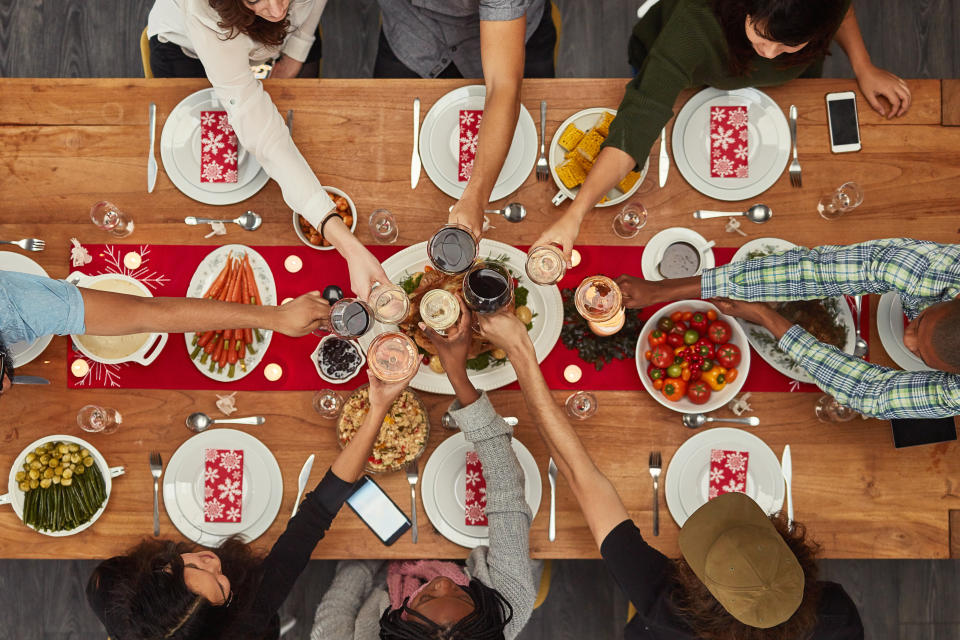 Cropped shot of a group of people making a toast at a dining table.