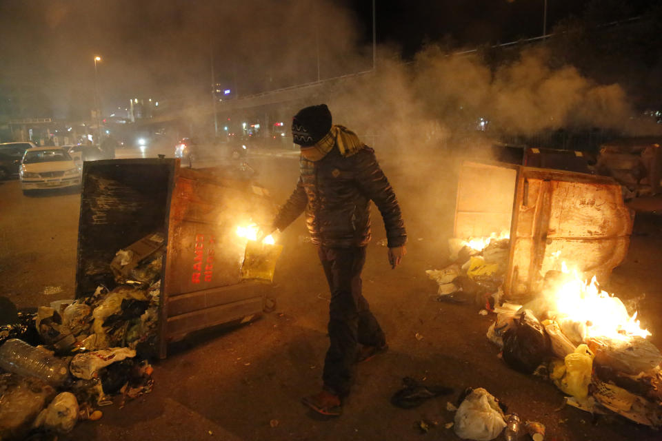 An anti-government protesters ignite trash in garbage container to block roads, during a protest against the new government, in Beirut, Lebanon, Tuesday, Jan. 21, 2020. Lebanon's prime minister designate Hassan Diab announced Tuesday a new government for the crisis-hit country, breaking a months-long impasse amid ongoing mass protests against the country's ruling elite. (AP Photo/Hussein Malla)