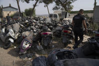 A Palestinian police officer inspects illegal motorcycles that police have newly confiscated as part of a wider crackdown on crime in Jenin, that are gathered in a scrap yard at the Beit Qad police station, north of the occupied West Bank city of Jenin, Sunday, Aug. 13, 2023. (AP Photo/Nasser Nasser)