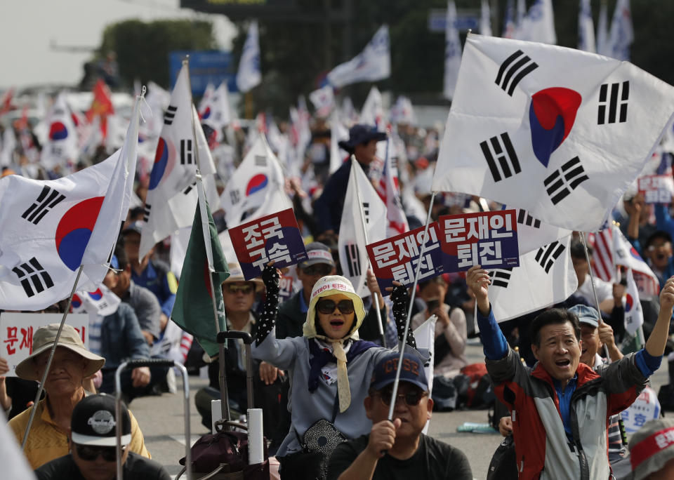 Protesters shout slogans as they wave national flags and signs during a rally denouncing South Korea's Justice Minister Cho Kuk in Seoul, South Korea, Saturday, Oct. 5, 2019. The letters read "Arrest Cho Kuk" and "Moon Jae-in, resign." (AP Photo/Lee Jin-man)