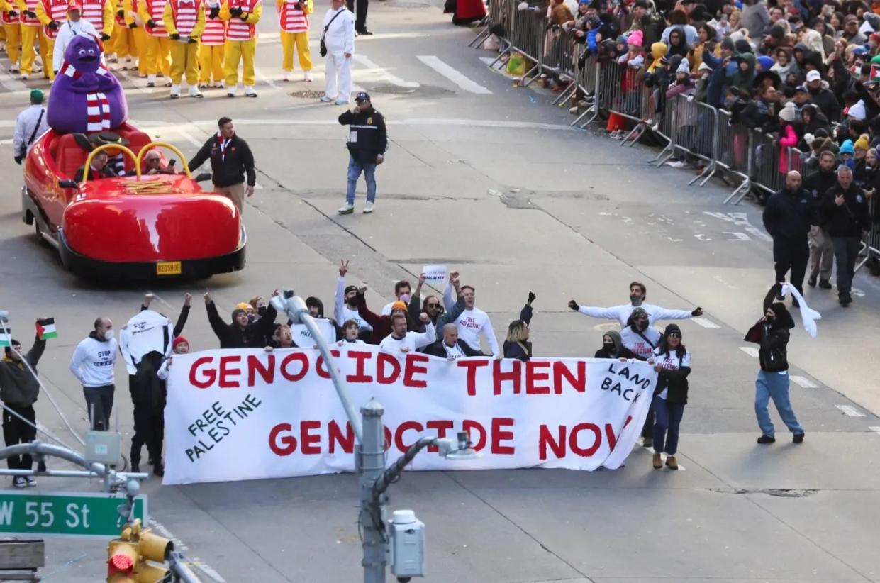 Pro-Palestinian protestors hold a banner that reads "genocide then, genocide now" at the Macy's Thanksgiving Day Parade