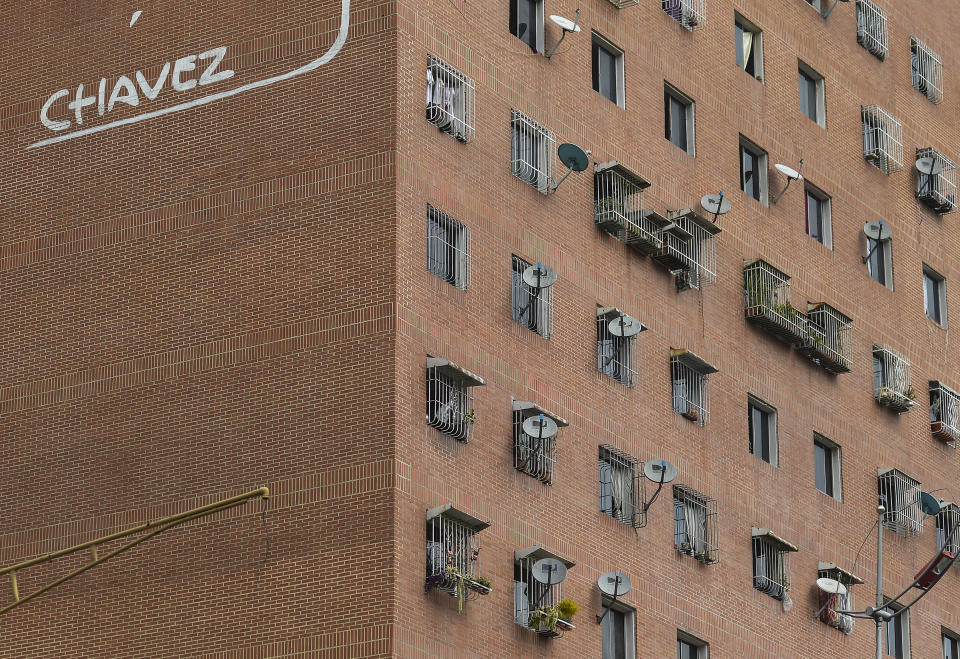 In this Jan. 9, 2020 photo, DirectTV dish antennas cover the exterior wall of an apartment building featuring the last name of late President Hugo Chavez in Caracas, Venezuela. Venezuelan President Maduro’s opponents want AT&T’s DirecTV unit to restore a number of channels it was required to take down from its lineup. But forcing AT&T to do the political bidding of Maduro’s foes could lead to retaliation and likely exit from a market where it has a whopping 44% market share. (AP Photo/Matias Delacroix)
