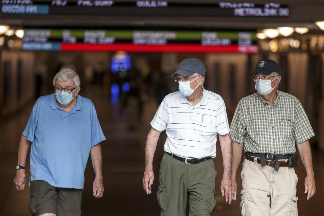 Three men, all masked, walk through a railway station.
