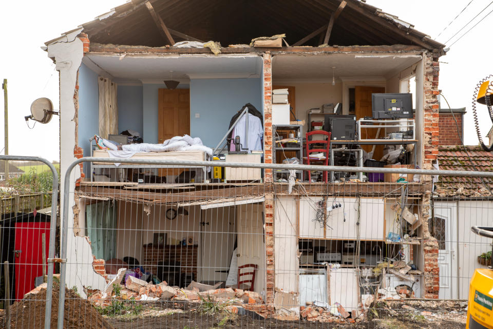 The house explosion in Kessingland, near Lowestoft, Suffolk. See SWNS copy SWCAexplosion: This is the devastation left when a huge explosion ripped through a family's home while they were watching TV. The entire gable end of the terraced home was blown out exposing the rooms and giving it the appearance of a giant dolls' house. A hero neighbour rescued the male homeowner from his burning home. The un-named neighbour ran into the partially collapsed and burning house and managed to extract its dazed occupant who had been watching TV.