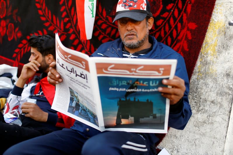 An Iraqi demonstrator reads Tuktuk newspaper during the ongoing anti-government protests, in Baghdad