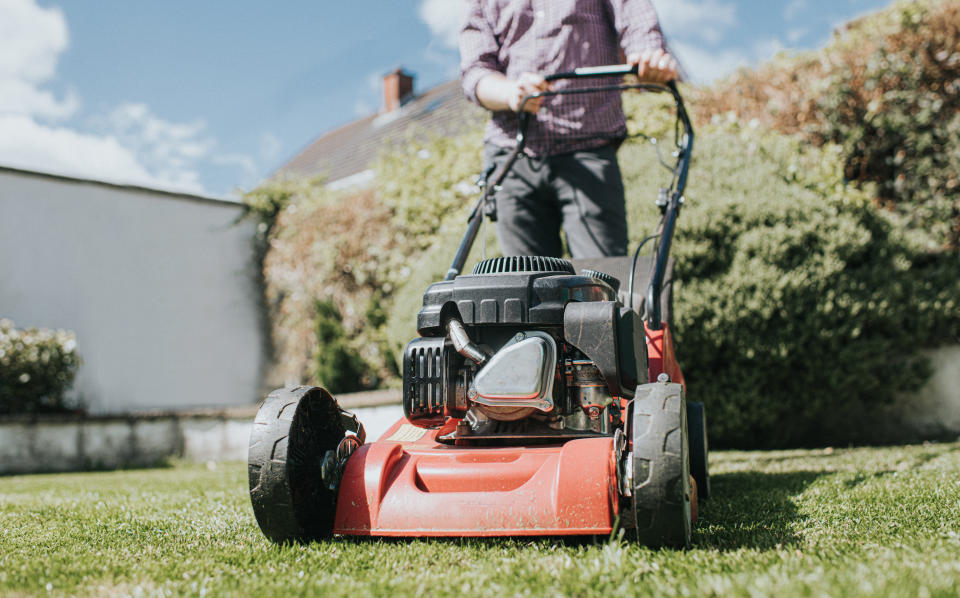 A close up shot of a man mowing the lawn.