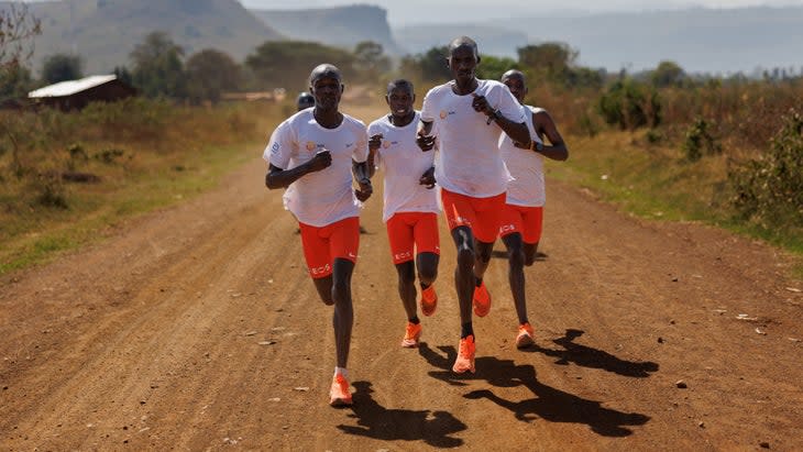 A group of four men run on dirt road