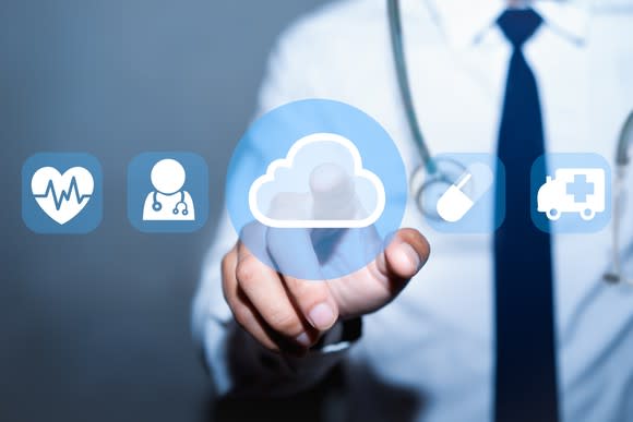 Doctor pointing to cloud icon next to healthcare icons.