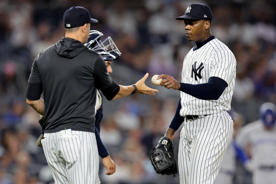 New York Yankees relief pitcher Aroldis Chapman (54) hands the ball to manager Aaron Boone (17) after being taken out of the game against the Toronto Blue Jays during the ninth inning at Yankee Stadium.