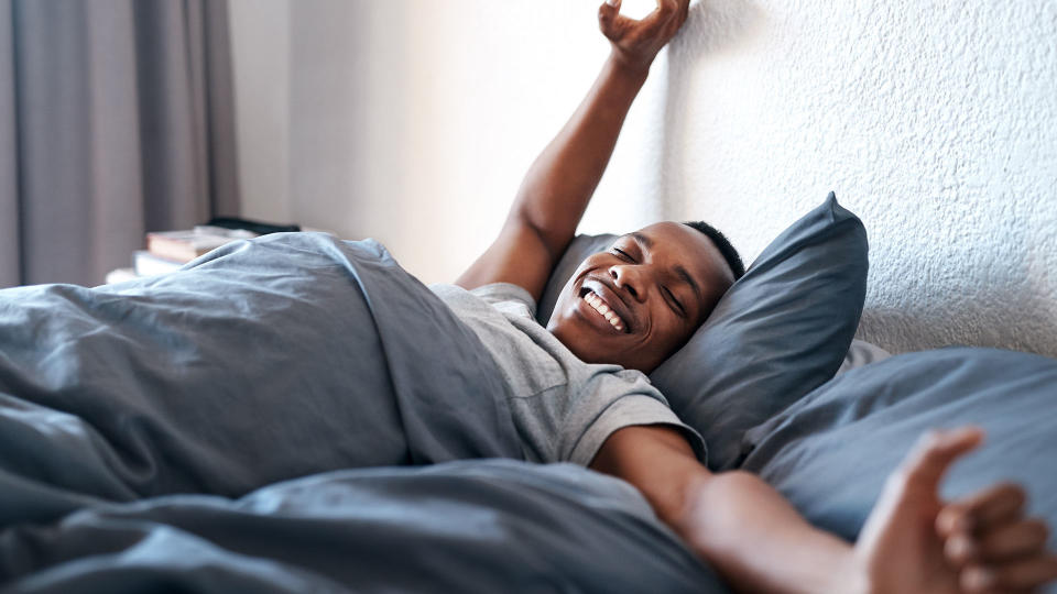 A man waking up in bed after a good night's sleep