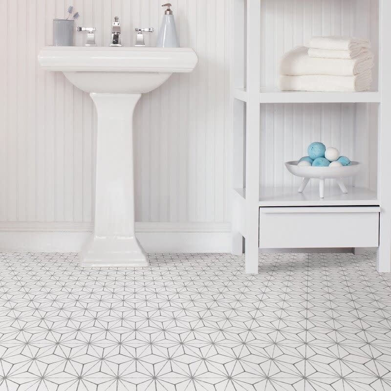 Bathroom with a pedestal sink, shelving unit with towels, and geometric patterned floor