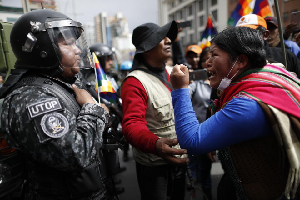 A supporter of Bolivia's former President Evo Morales yells at a police officer, telling him to respect the nation's indigenous people in La Paz, Bolivia, Tuesday, Nov. 12, 2019. Former President Evo Morales, who transformed Bolivia as its first indigenous president, flew to exile in Mexico on Tuesday after weeks of violent protests, leaving behind a confused power vacuum in the Andean nation. (AP Photo/Natacha Pisarenko)