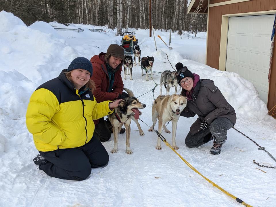 Abby and her travel companions petting the sled dogs in the snow