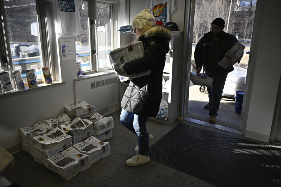 Advertising and Circulation Director Rosemary Scanlon carries bundles of paper into The American Museum of Tort Law, Friday, Feb. 3, 2023, in Winsted, Conn. At a time that local newspapers are dying at an alarming rate, longtime activist Ralph Nader is helping give birth to one. Nader put up $15,000 to help launch The Winsted Citizen and hired a veteran Connecticut journalist, Andy Thibault, to put it together. (AP Photo/Jessica Hill)