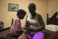 Deported from the United States a day before, Delta de Leon and her 2-year-old daughter Chloe, look at pictures from their time in Chile, in their temporary bedroom, at a relative's home in Port-au-Prince, Haiti, Thursday, Sept. 23, 2021. Chole was born in Chile. (AP Photo/Joseph Odelyn)