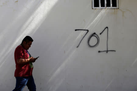 A man walks by the number 701, referring to the world's billionaires ranking given by Forbes magazine in 2009 to Mexican drug lord Joaquin 'El Chapo' Guzman, ahead of the visit of Mexico's President Andres Manuel Lopez Obrador to Badiraguato, in the Mexican state of Sinaloa, Mexico February 15, 2019. REUTERS/Daniel Becerril