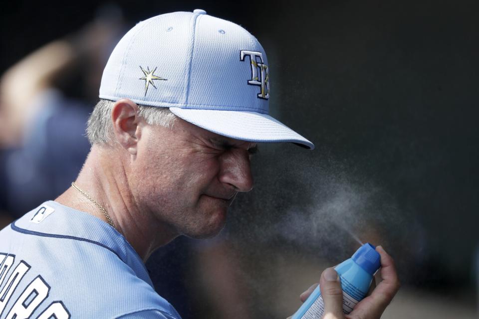 Tampa Bay Rays coach Matt Quatraro applies sunscreen before a spring training game on Feb. 25, 2020, in Sarasota, Fla.