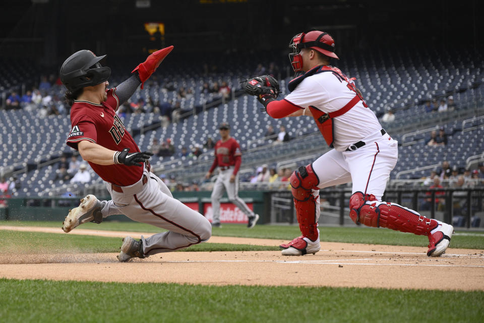 Arizona Diamondbacks' Corbin Carroll starts his slide towards home to score on a single by Christian Walker as Washington Nationals catcher Riley Adams waits for the throw during the first inning of a baseball game, Thursday, June 22, 2023, in Washington. (AP Photo/Nick Wass)