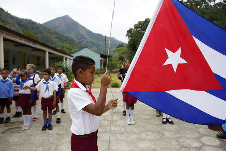 A boy raises the Cuban flag during a daily ceremony held at a school in the village of Santo Domingo, in the Sierra Maestra, Cuba, April 2, 2018. REUTERS/Alexandre Meneghini