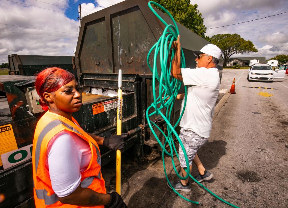 Tamika Lewis, a recycling attendant, left, watches as Joey Belle throws a water hose in a trash compactor as people were dropping off household garbage and recyclables at the Baseline Recycling Center Friday morning, May 13.