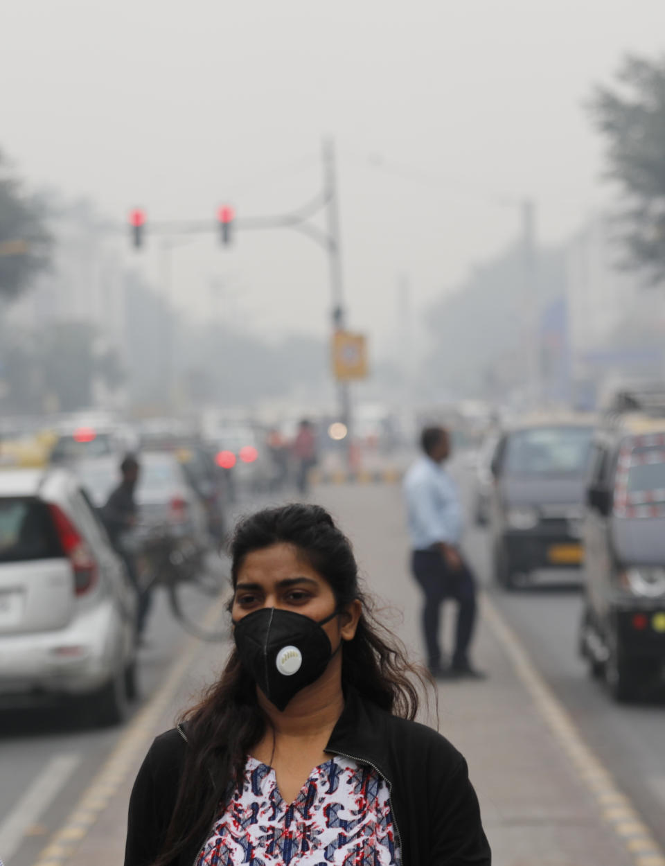 A commuter walks wearing a pollution mask amidst thick layer of smog in New Delhi, India, Thursday, Nov. 14, 2019. Schools in India's capital have been shut for Thursday and Friday after air quality plunged to a severe category for the third consecutive day, enveloping New Delhi in a thick gray haze of noxious air. (AP Photo/Manish Swarup)