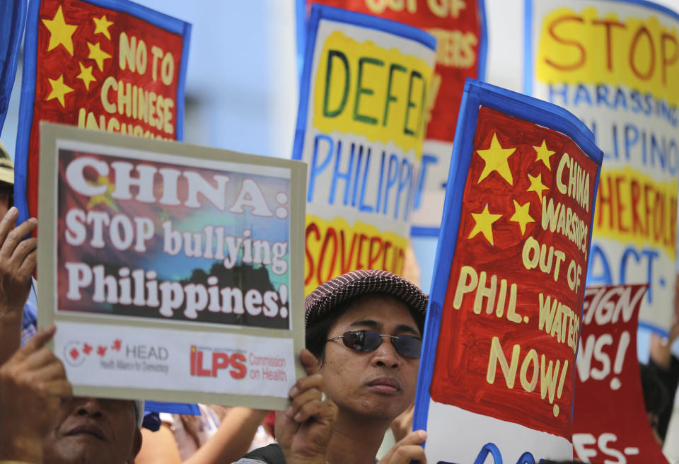 A Filipino protester holds placards with slogans during a rally outside the Chinese consulate at the financial district of Makati, south of Manila, Philippines on Tuesday, April 22, 2014. The group is demanding an end to China's alleged incursions in the South China Sea and to press the Chinese government to respect the arbitral process under the United Nations Convention on the Law of the Sea. (AP Photo/Aaron Favila)