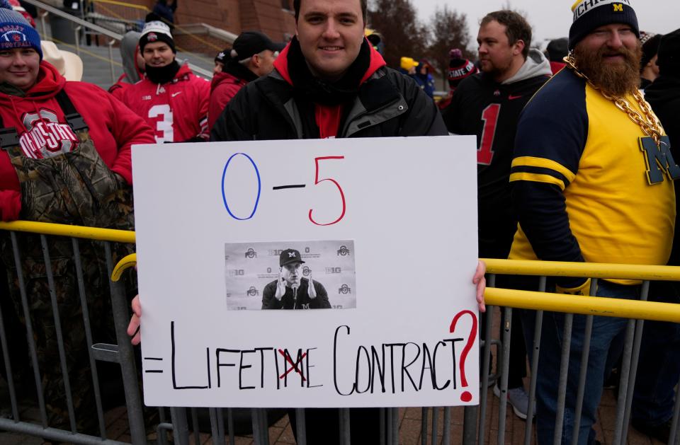 Ohio State Buckeyes fan Chander Bauer of Ft. Wayne, Ind. holds a Michigan Wolverines head coach Jim Harbaugh sign prior to the NCAA football game against the Michigan Wolverines at Michigan Stadium in Ann Arbor on Saturday, Nov. 27, 2021.