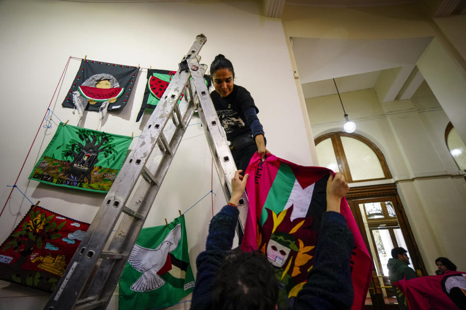 Varios trabajadores preparan obras para una exposición llamada “Desde todos los ríos hasta todos los mares. Gráfica en Solidaridad con Palestina” en el Archivo Nacional de Chile en Santiago, Chile, el miércoles 19 de junio de 2024. (AP Foto/Esteban Félix)