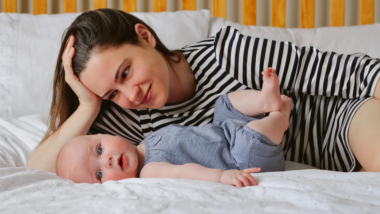 Madre acostada en su cama mirando amorosamente a su bebé