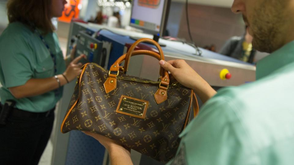 Flughafen Düsseldorf: Ein Zollbeamter hält eine gefälschte Louis-Vuitton-Handtasche in der Hand. Foto: Matthias Balk