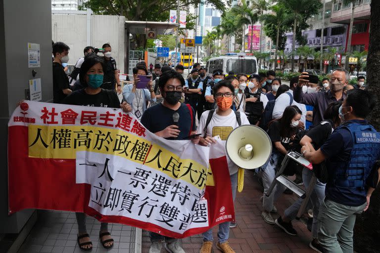 Manifestantes a favor de la democracia son rodeados por agentes de policía mientras llevan una pancarta contra la elección del jefe del ejecutivo cerca de un colegio electoral en Hong Kong, el domingo 8 de mayo de 2022.