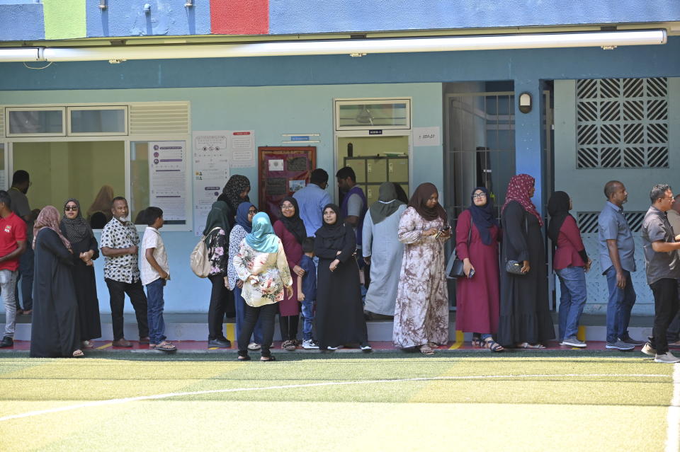Maldivians stand in a queue ito cast their votes in Male, Maldives, Saturday, Sept. 30, 2023. Maldivians are voting in the runoff presidential election that has turned into a virtual referendum on which regional power, India or China, will have the biggest influence in the Indian Ocean archipelago nation. (AP Photo/Mohamed Sharuhaan)