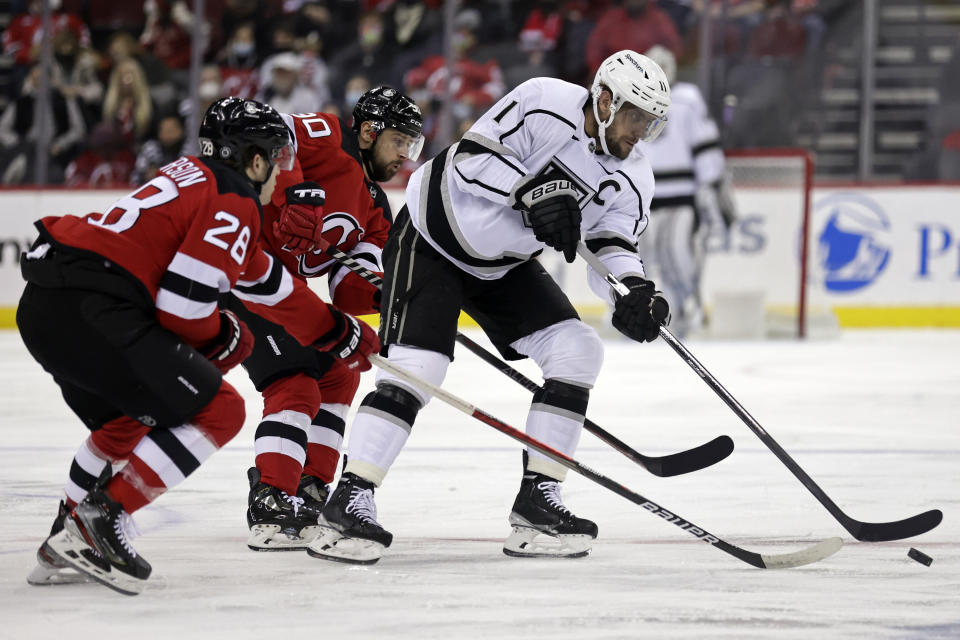 Los Angeles Kings center Anze Kopitar (11) passes the puck in front of New Jersey Devils defenseman Damon Severson during the first period of an NHL hockey game Sunday, Jan. 23, 2022, in Newark, N.J. (AP Photo/Adam Hunger)
