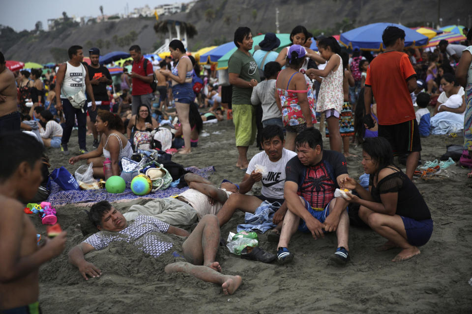In this Feb. 16, 2020 photo, beachgoers relax in the sand at Agua Dulce beach in Lima, Peru. While Lima's elite passes its summer weekends in gated beach enclaves south of the Peruvian capital, the working class jams by the thousands on this municipal beach. (AP Photo/Rodrigo Abd)