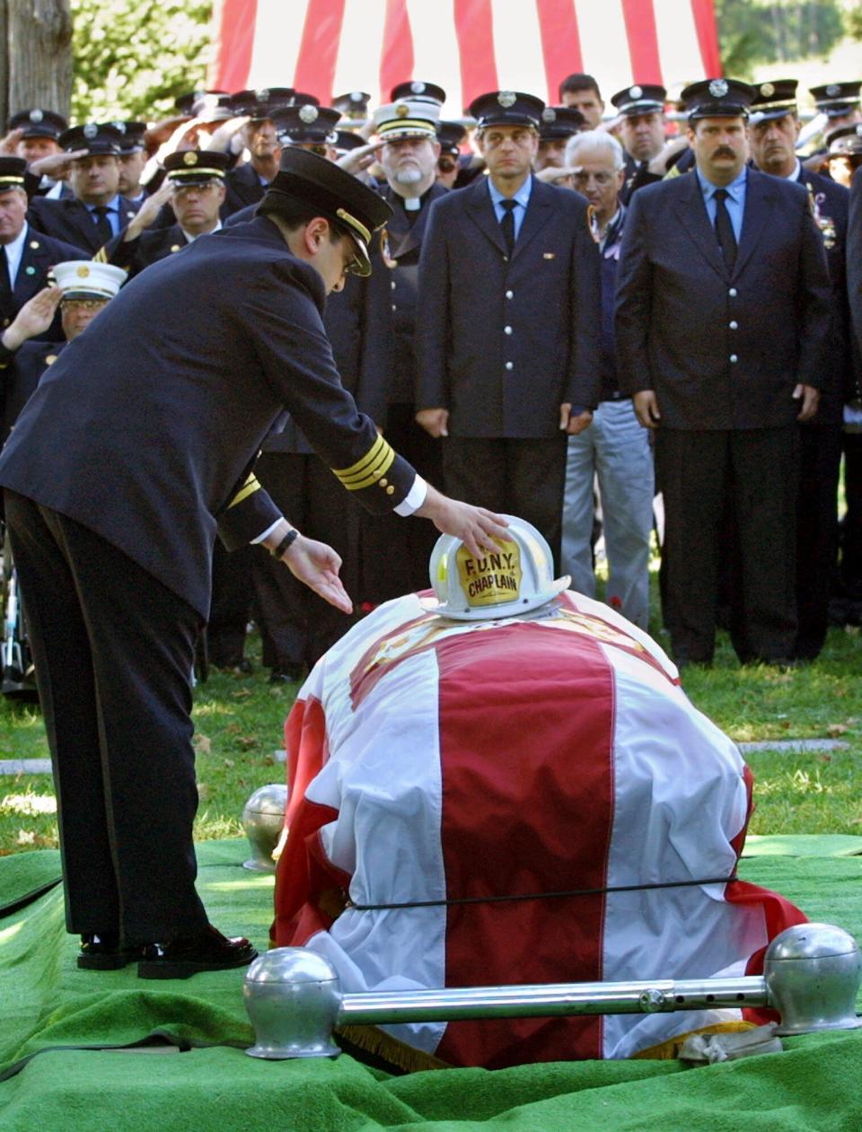 FILE - In this Saturday, Sept. 15, 2001 file photo, Father Mychal Judge's helmet is placed on his coffin as representatives of various fire brigades in New Jersey form an honor guard at the Franciscan Fathers burial site in Totawa, N.J. Judge, 68, died Tuesday as he was administering last rites to a firefighter mortally injured in the attack on the World Trade Center. (AP Photo/Stuart Ramson, File)