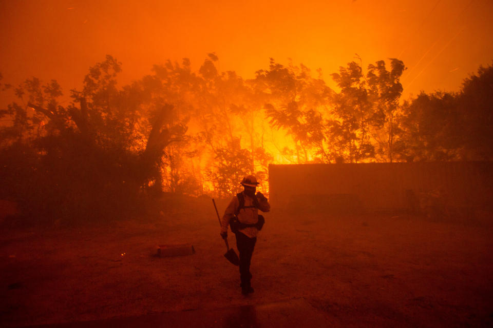 A firefighter walks near an area burning in the Hughes Lake fire in Angeles National Forest on Wednesday, Aug. 12, 2020, north of Santa Clarita, Calif. (AP Photo/Ringo H.W. Chiu)