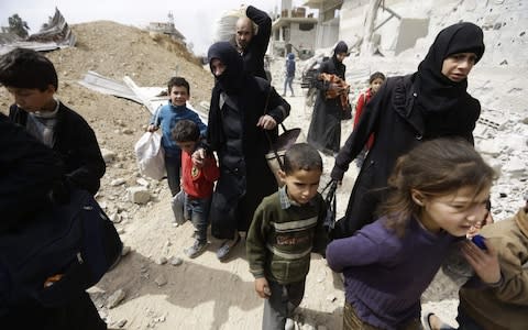 Syrians from rebel-held Eastern Ghouta arrive at the regime-held checkpoint in Adra - Credit: AFP