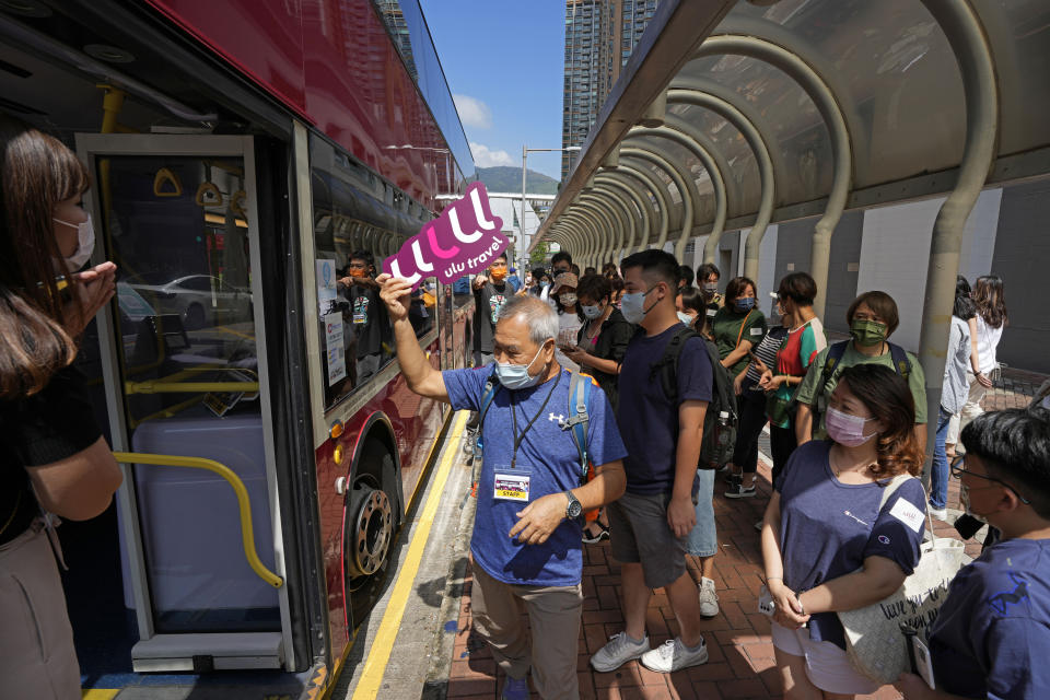 Passengers line up for a bus tour in Hong Kong, Saturday, Oct. 16, 2021. Travel-starved, sleep-deprived residents might find the new Hong Kong bus tour to be a snooze. The 47-mile, five-hour ride on a double-decker bus around the territory is meant to appeal to people who are easily lulled asleep by long rides. (AP Photo/Kin Cheung)