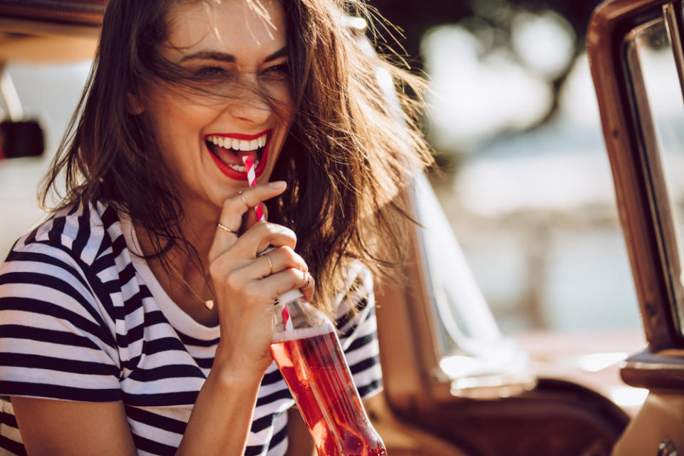 Young woman having a soda in a glass with a straw on a sunny day