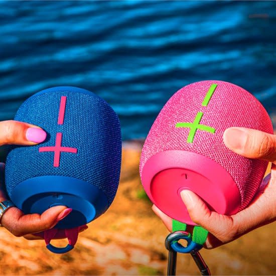 models holding pink and blue bluetooth speakers