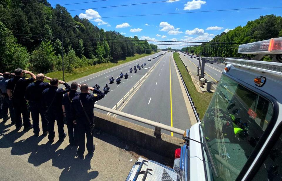 Firefighters and sheriff deputies on the Cindy Lane Bridge salute a processional on I-77 for Deputy U.S. Marshal Thomas “Tommy” Weeks Jr. Weeks, of Mooresville, was one of four officers fatally shot while serving a warrant in east Charlotte on April 29. Khadejeh Nikouyeh/knikouyeh@charlotteobserver.com