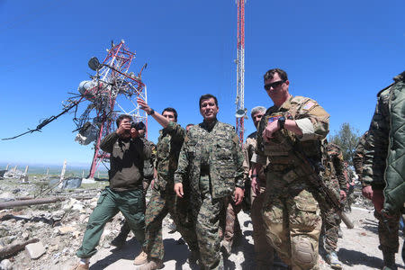 A U.S. military commander (R) walks with a commander (C) from the Kurdish People's Protection Units (YPG) as they inspect the damage at YPG headquarters after it was hit by Turkish airstrikes in Mount Karachok near Malikiya, Syria April 25, 2017. REUTERS/ Rodi Said