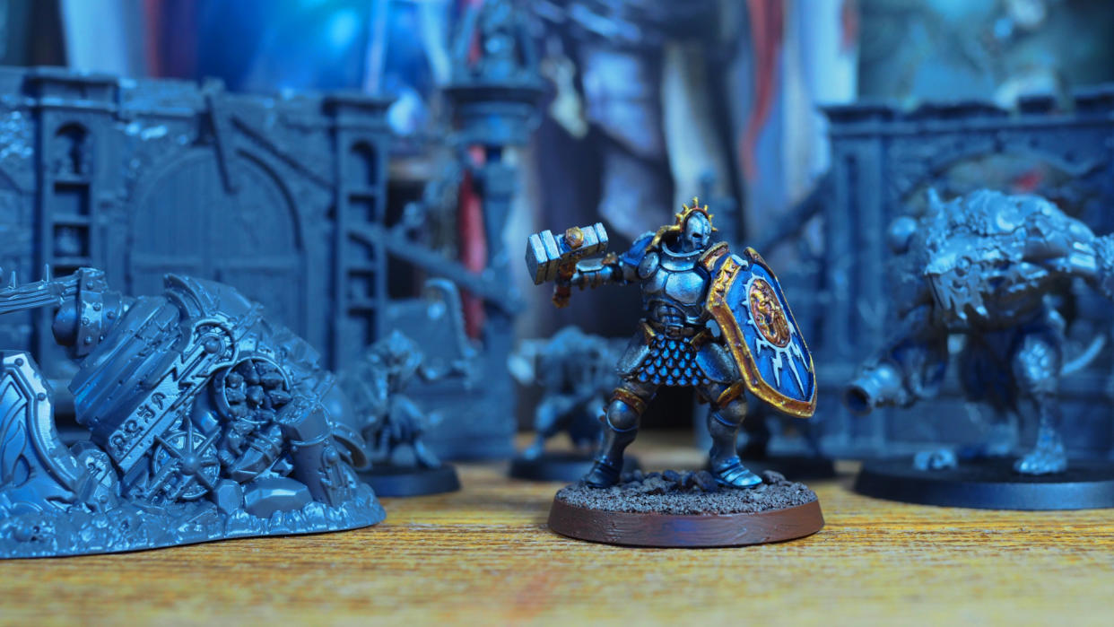  A painted Warhammer Age of Sigmar Stormcast Eternal model stands against Skaven miniatures from the Skaventide box set. 