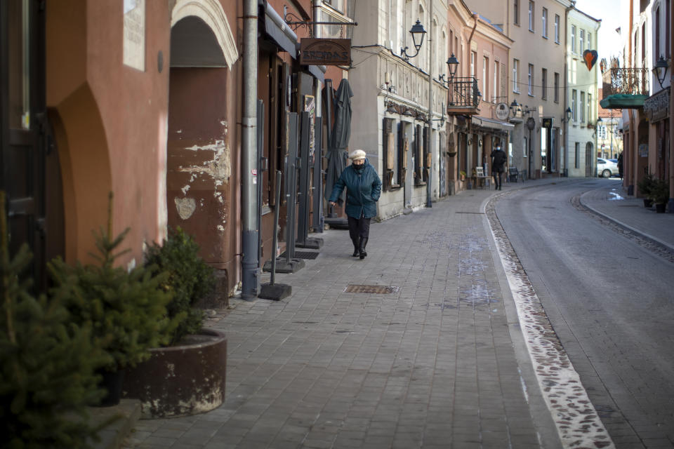 A woman wearing a face mask to protect against coronavirus, walks along an empty street in Old Town in Vilnius, Lithuania, Tuesday, March 9, 2021. The quarantine restrictions have contributed to slowing the spread of the coronavirus (COVID-19) in Lithuania, but morbidity rates are still high. (AP Photo/Mindaugas Kulbis)