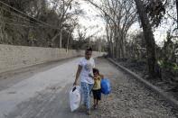 A boy holds on to his mother as they flee from their town following Taal Volcano's eruption, in Talisay