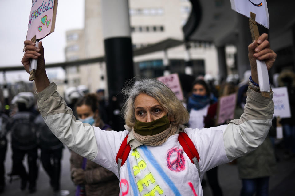 A protester holds up placards during an unauthorised demonstration against COVID-19 restrictive measures in Brussels, Sunday, Jan. 31, 2021. According to Belgian media around 200 people have been arrested for trying to join a protest against restrictive measures implemented in the country in order to fight the virus, such as a 10pm curfew or the closing of bars and restaurants. (AP Photo/Francisco Seco)