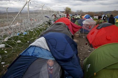 A migrant who is waiting to cross the Greek-Macedonian sits in his tent by the border fence at a makeshift camp, near the village of Idomeni, Greece, in this March 4, 2016 file photo. REUTERS/Marko Djurica/Files