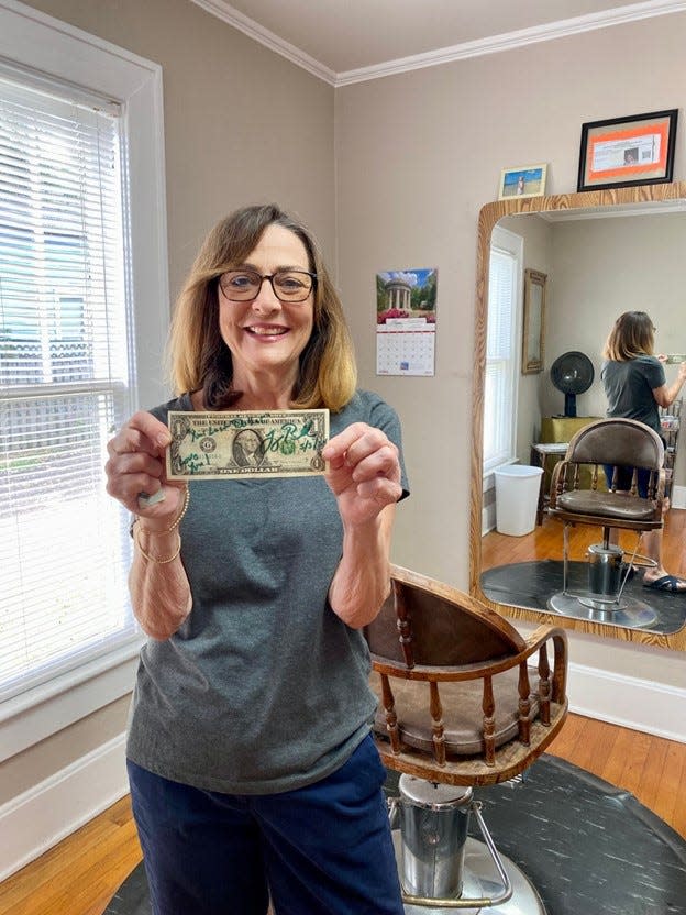 Debbie Revell, owner of Southern Accents Salon, holds her “last dollar” made before retiring.
