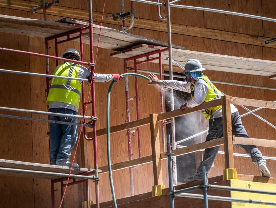 Workers pull a hose at the Sonrisa affordable housing project in 2022 on O Street in Sacramento. CEQA reformers say the environmental law stymies housing production in a state without enough places for people to live. 